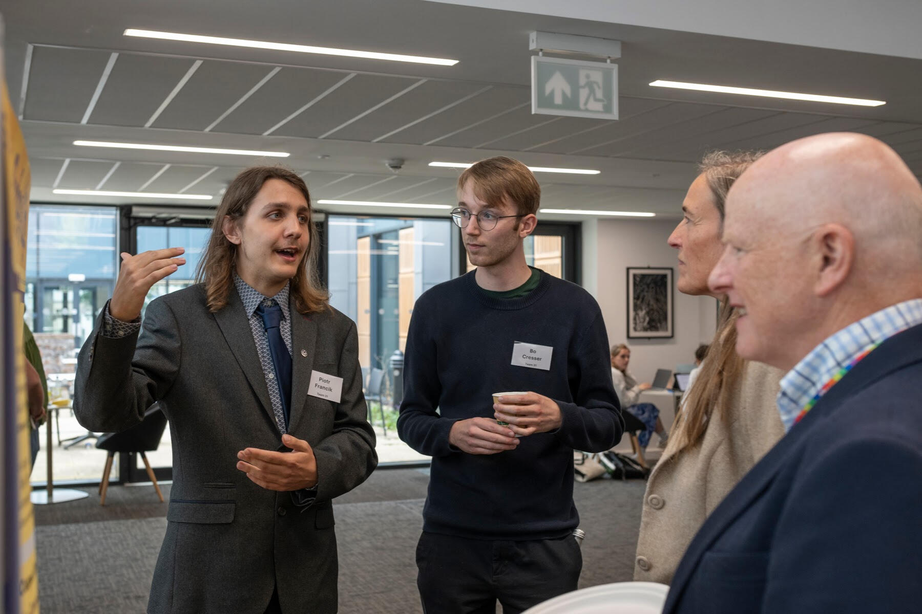 Piotr and Bo are talking with Aegis Professor Undergraduate Competition judges about their poster and business idea